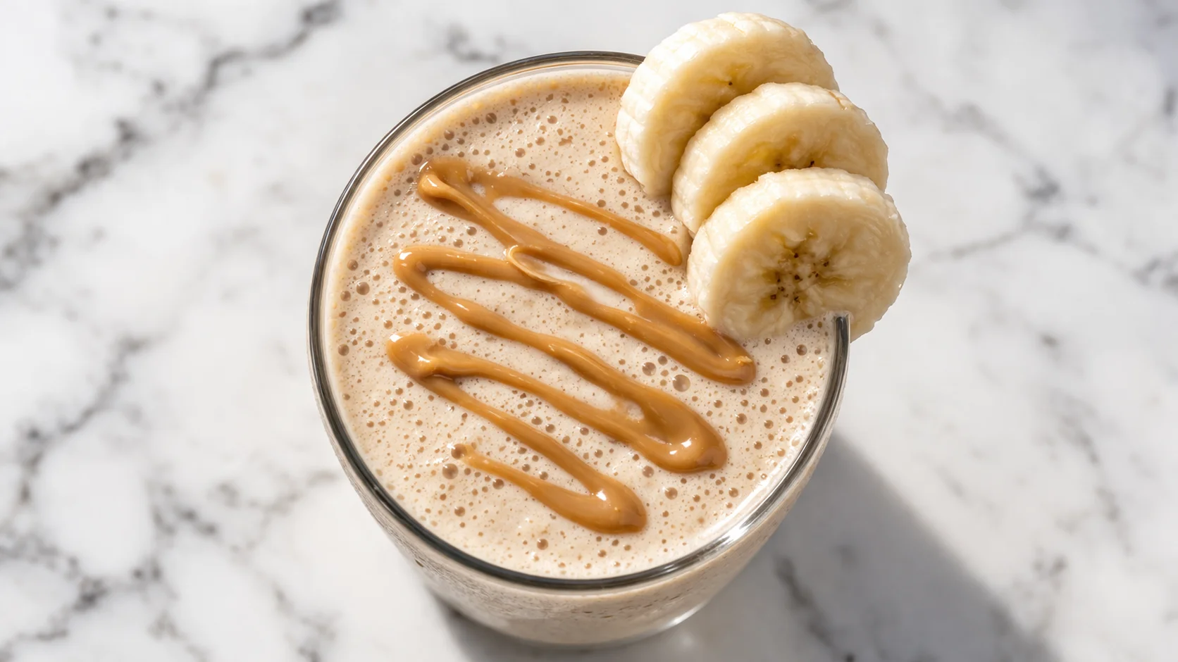 Gros plan sur un milkshake banane cacahuète protéiné avec topping de beurre de cacahuète