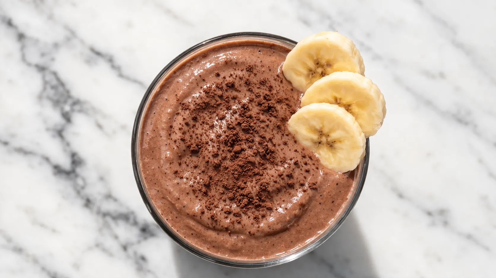 Gros plan sur un smoothie chocolat-banane protéiné avec tranches de banane en garniture