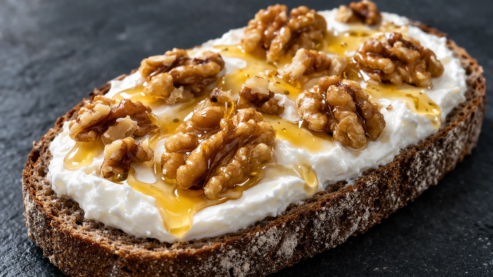 Gros plan sur une tartine fromage blanc miel-noix, texture épaisse et crémeuse du fromage blanc avec cerneaux de noix et miel brillant visibles sur pain grillé